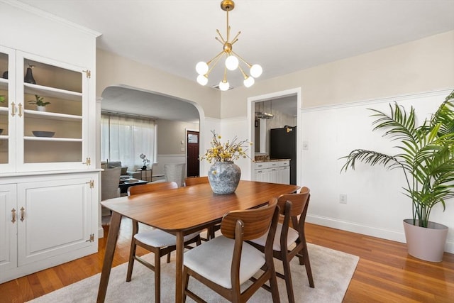 56 Beach St, Woburn, MA 01801 - dining area with arched walkways, light wood-type flooring, a chandelier, and a wainscoted wall