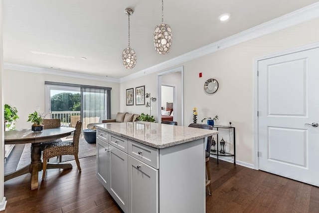 kitchen featuring a kitchen island, ornamental molding, light stone countertops, dark wood-style floors, and decorative light fixtures