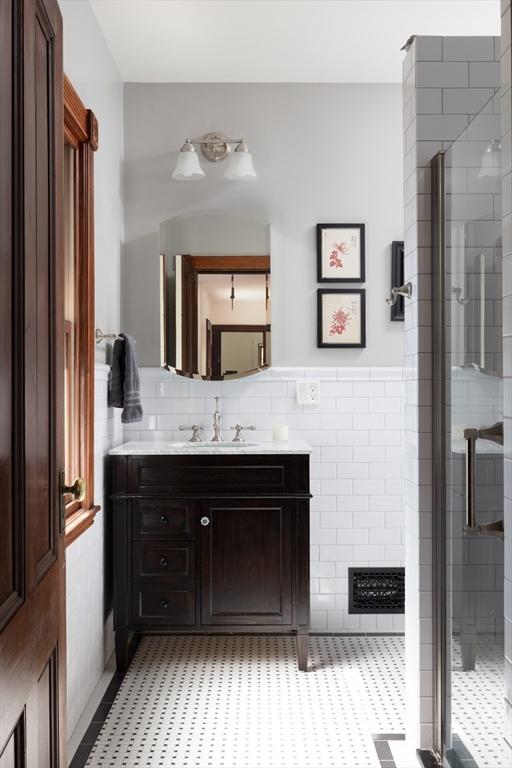 bathroom featuring a shower stall, vanity, tile walls, and wainscoting