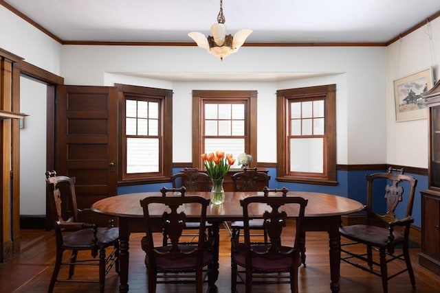 dining space with a wainscoted wall, wood finished floors, crown molding, and a chandelier
