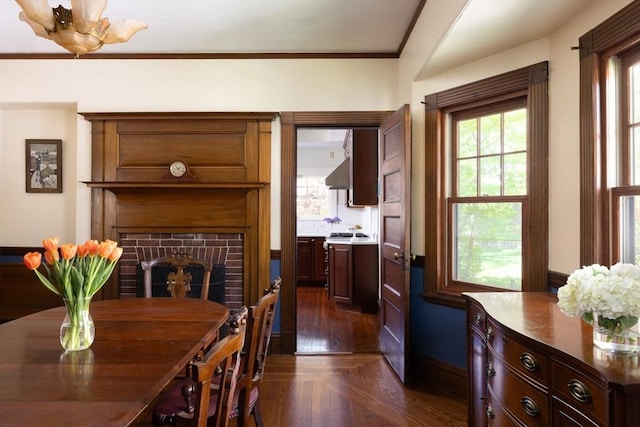 dining room with a brick fireplace and crown molding