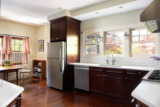 kitchen with stainless steel appliances, a sink, exhaust hood, light countertops, and decorative backsplash