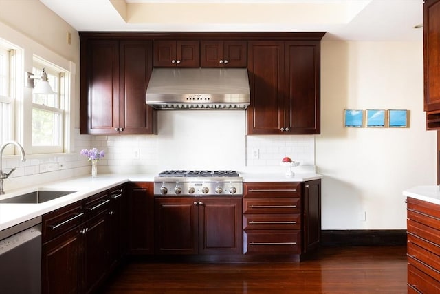 kitchen featuring under cabinet range hood, a sink, stainless steel appliances, dark wood-style floors, and light countertops