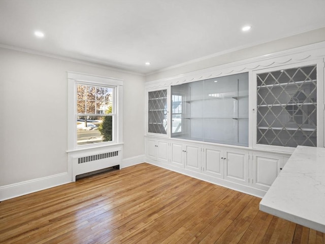 unfurnished dining area with radiator, ornamental molding, and light hardwood / wood-style floors