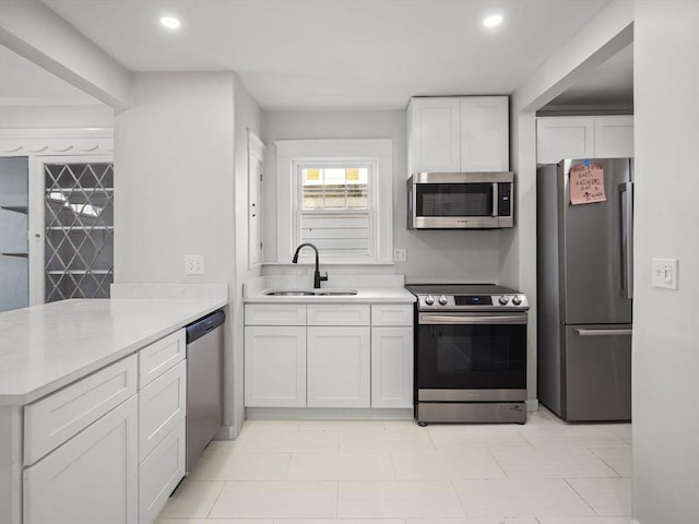 kitchen with white cabinetry, appliances with stainless steel finishes, kitchen peninsula, and sink