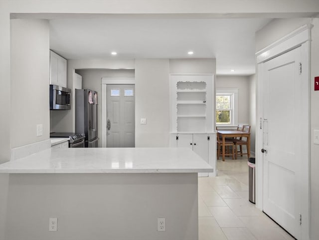 kitchen featuring white cabinetry, appliances with stainless steel finishes, light tile patterned floors, and kitchen peninsula