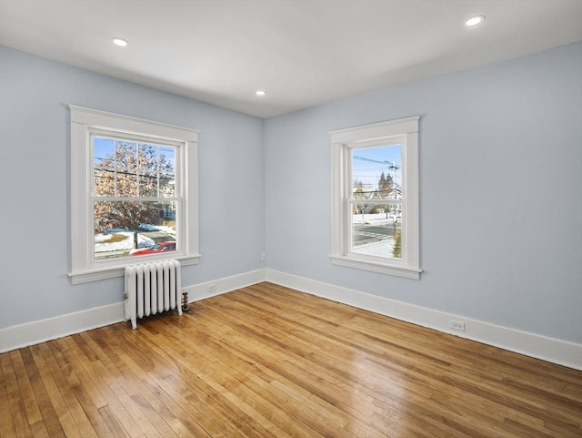 empty room with radiator heating unit, light hardwood / wood-style floors, and plenty of natural light