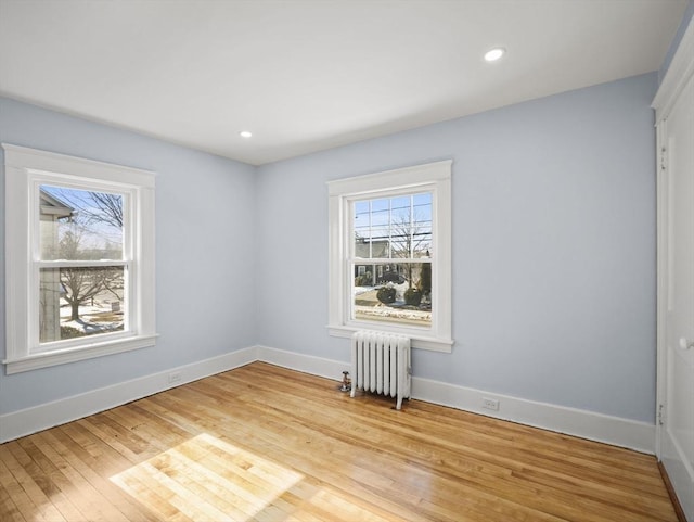 unfurnished room featuring radiator and light hardwood / wood-style flooring