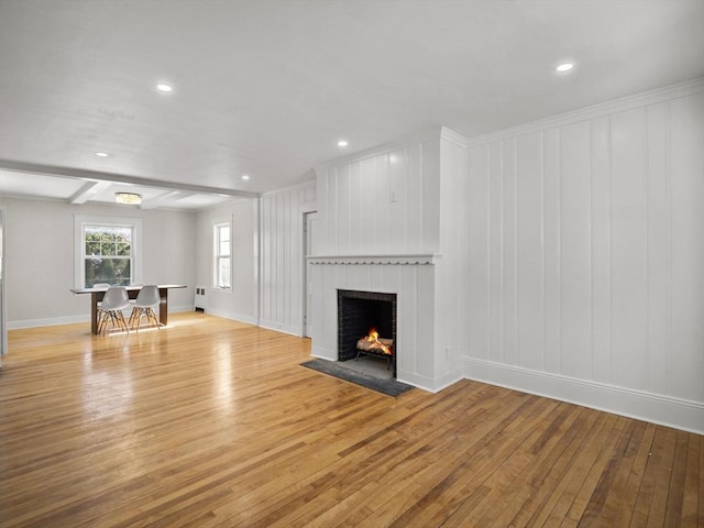 unfurnished living room with a brick fireplace, light hardwood / wood-style floors, and beamed ceiling