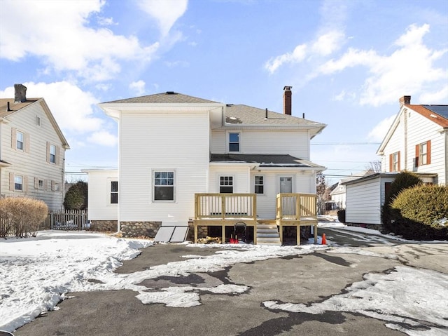 snow covered rear of property with a deck