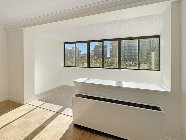 interior space with a textured ceiling, crown molding, and radiator heating unit