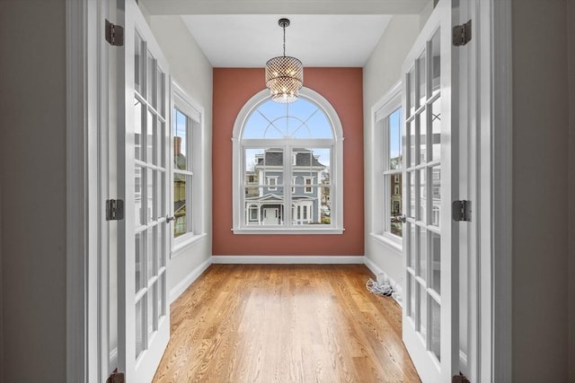 63 Perrin St, Boston, MA 02119 - unfurnished dining area featuring a chandelier, healthy amount of natural light, light wood-style flooring, and baseboards