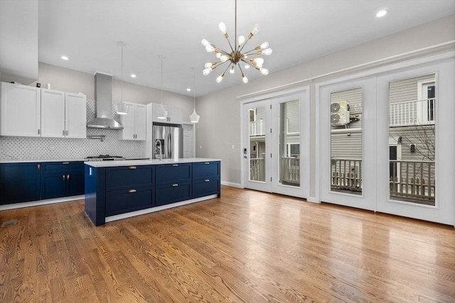 63 Perrin St, Boston, MA 02119 - kitchen featuring wall chimney exhaust hood, blue cabinets, stainless steel refrigerator with ice dispenser, light countertops, and white cabinets
