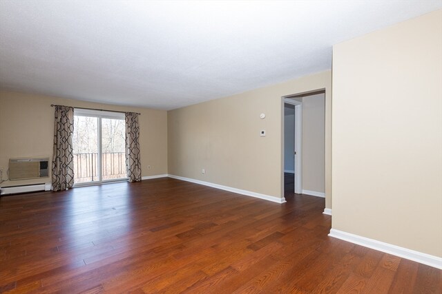 unfurnished room featuring dark hardwood / wood-style flooring, baseboard heating, and a wall mounted AC