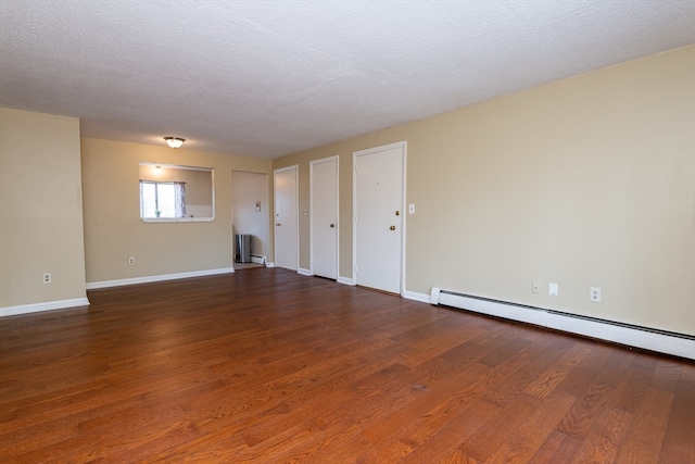 empty room featuring a textured ceiling, dark hardwood / wood-style flooring, and a baseboard radiator