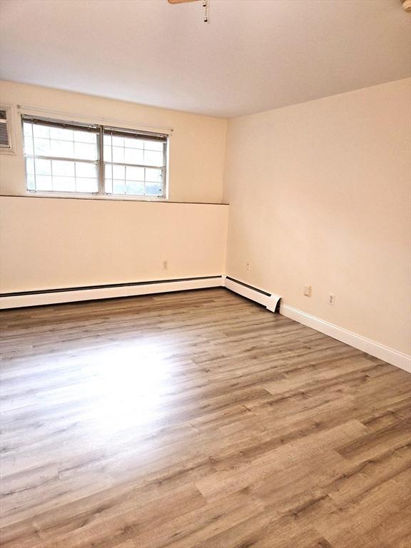 6 Venice St Unit F2, Danvers, MA 01923 - spare room featuring plenty of natural light, baseboards, wood finished floors, and baseboard heating