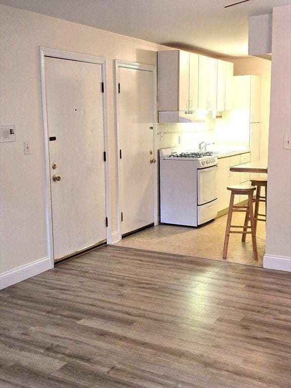 6 Venice St Unit F2, Danvers, MA 01923 - kitchen featuring white range with gas cooktop, light wood-style flooring, baseboards, and white cabinetry