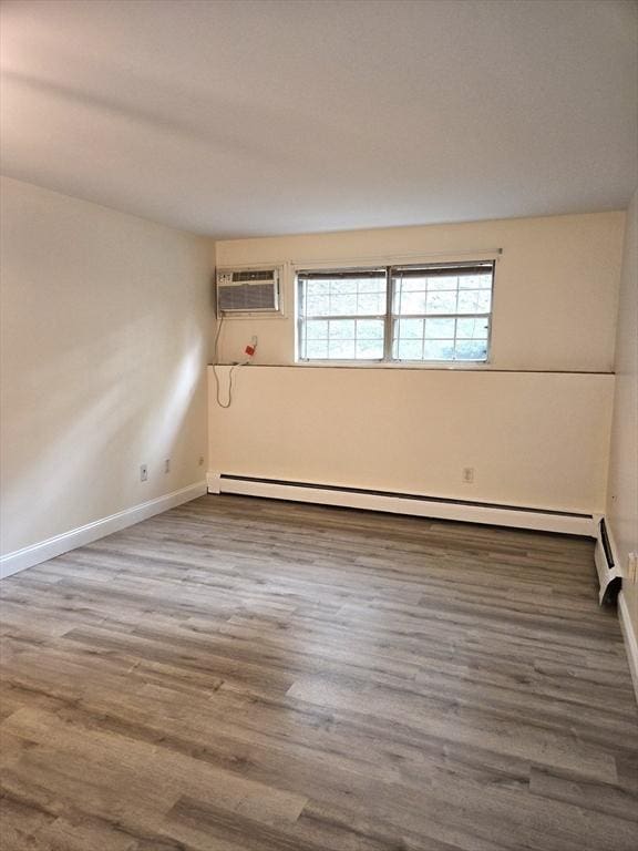 6 Venice St Unit F2, Danvers, MA 01923 - empty room with a wall mounted AC, a baseboard heating unit, baseboards, and wood finished floors
