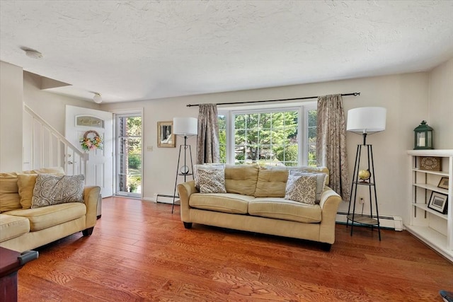17 York Towne Ter Unit 17, Holden, MA 01520 - living area with a baseboard radiator, wood finished floors, stairs, plenty of natural light, and a textured ceiling