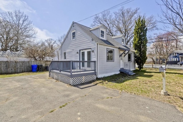 view of front of property with roof with shingles, fence, a front yard, and a deck