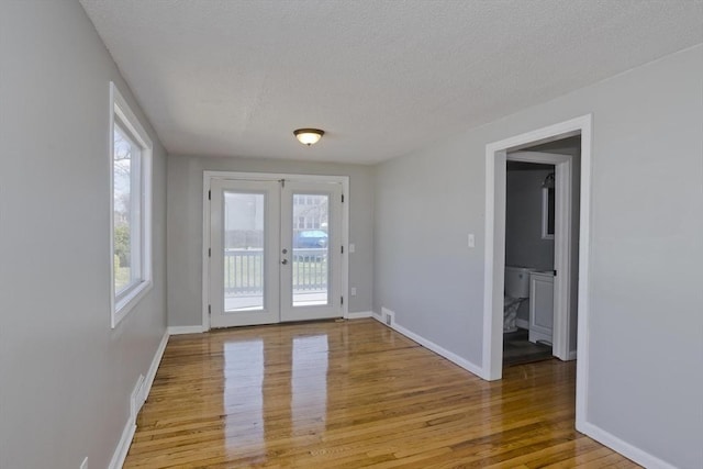 doorway featuring french doors, a textured ceiling, baseboards, and wood finished floors