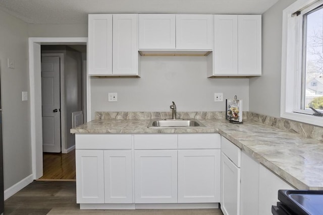 kitchen with a sink, light wood-style flooring, white cabinets, and light countertops