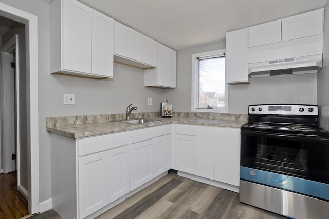 kitchen featuring a sink, light countertops, dark wood finished floors, electric stove, and under cabinet range hood