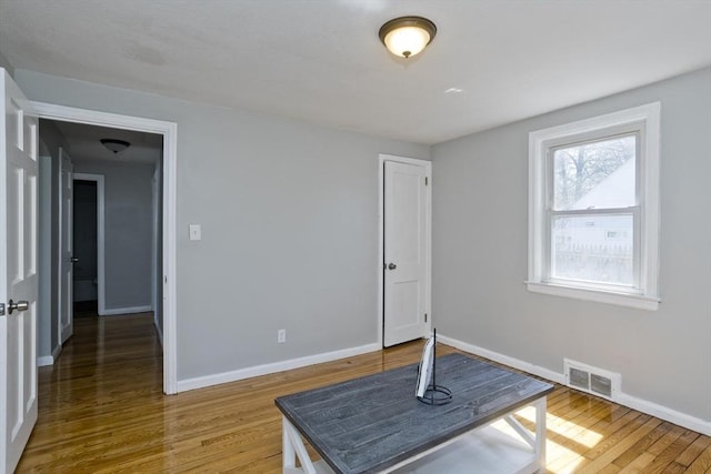 interior space with baseboards, wood finished floors, and visible vents