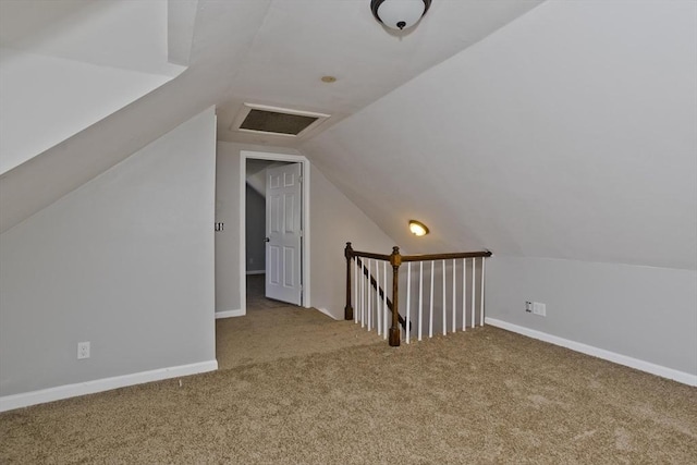 additional living space with baseboards, carpet, attic access, and lofted ceiling