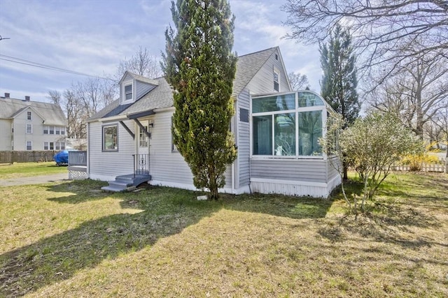 view of side of home with a lawn and a shingled roof