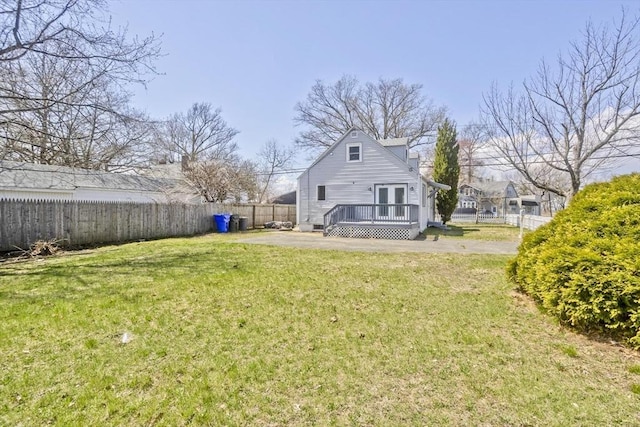rear view of house featuring a fenced backyard, a lawn, a deck, and french doors