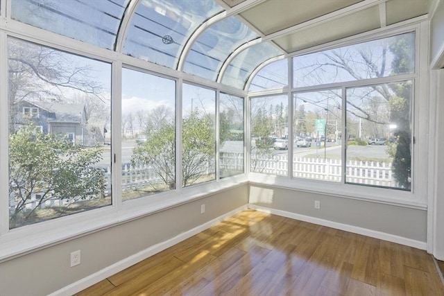 unfurnished sunroom featuring baseboards and wood finished floors
