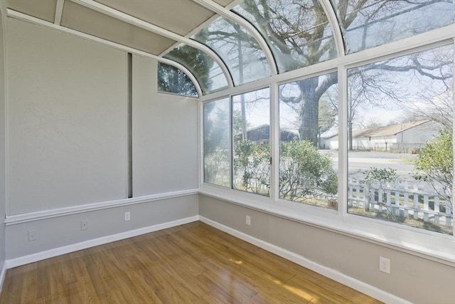 unfurnished sunroom featuring baseboards and wood finished floors
