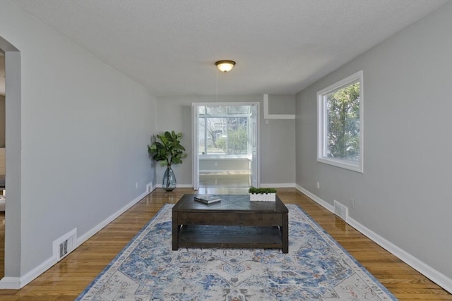 sitting room with visible vents, a healthy amount of sunlight, and wood finished floors