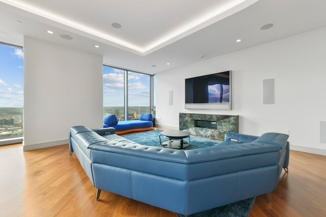 living room featuring floor to ceiling windows, light hardwood / wood-style flooring, and a high end fireplace