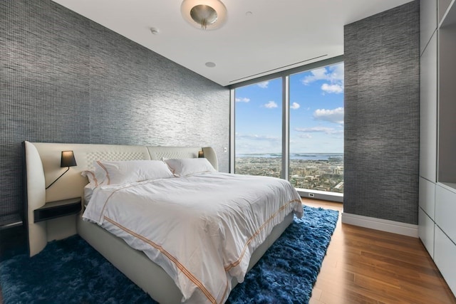 bedroom with expansive windows and hardwood / wood-style floors