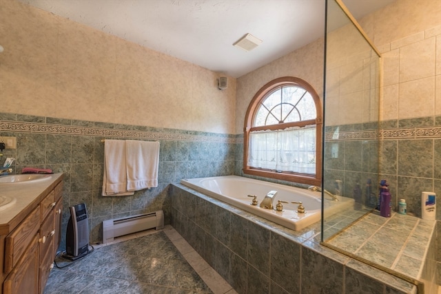 bathroom featuring vanity, tiled bath, baseboard heating, and tile walls