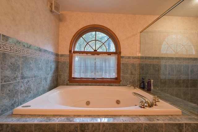 bathroom with tile walls and a relaxing tiled tub