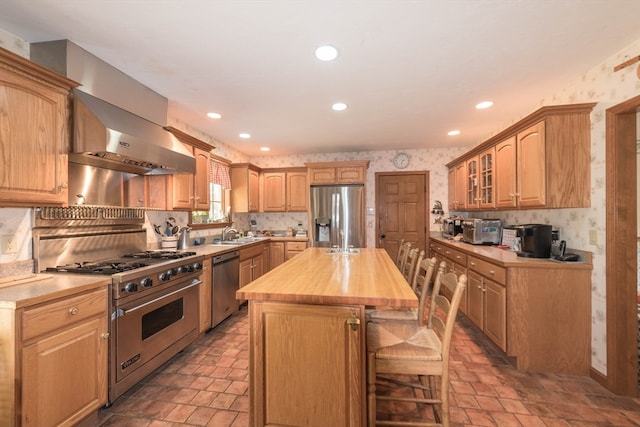 kitchen with appliances with stainless steel finishes, decorative backsplash, a breakfast bar, butcher block counters, and a center island