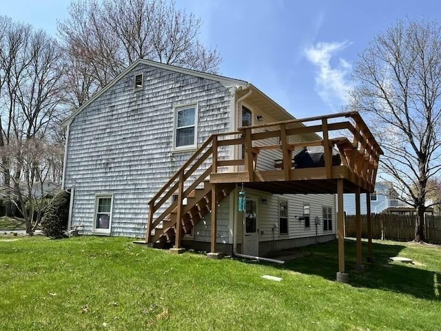 rear view of property with a lawn, a deck, stairway, and fence