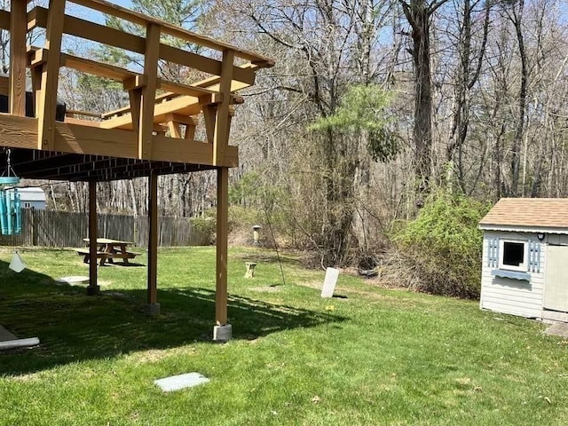 view of yard with a storage unit, an outdoor structure, fence, and a deck