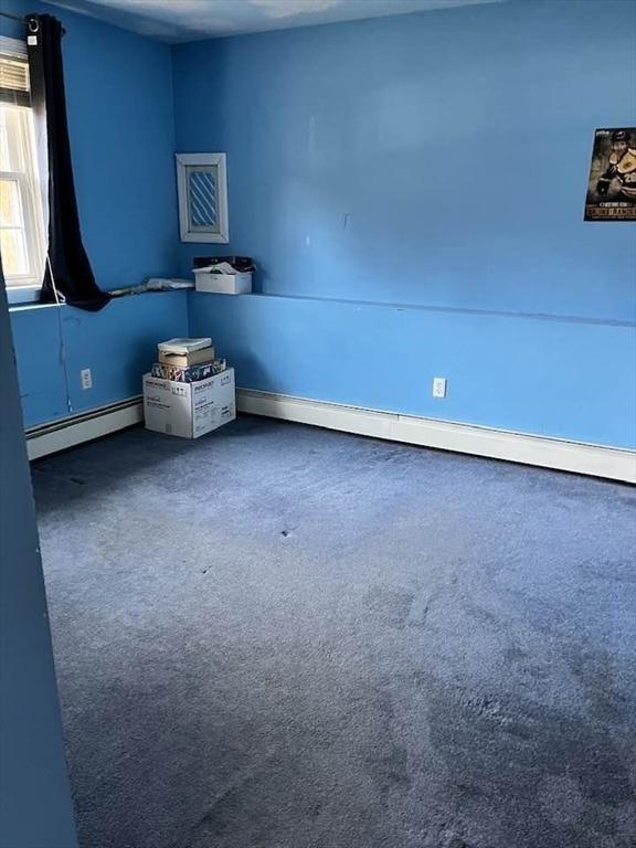 carpeted empty room with baseboard heating