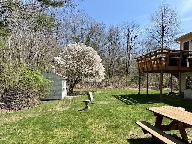 view of yard featuring a storage shed, a wooden deck, and an outbuilding