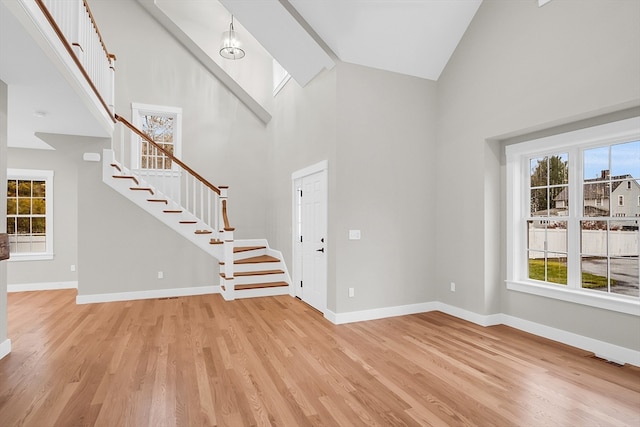 entrance foyer featuring a wealth of natural light, beam ceiling, light wood-type flooring, and high vaulted ceiling