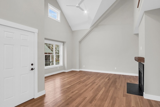 unfurnished living room featuring hardwood / wood-style flooring, plenty of natural light, and high vaulted ceiling