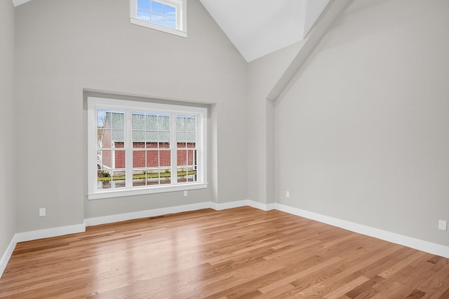 unfurnished room with high vaulted ceiling and light hardwood / wood-style flooring