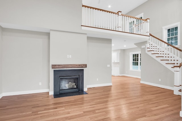 unfurnished living room with a towering ceiling and light hardwood / wood-style flooring