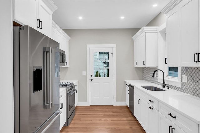 kitchen with stainless steel appliances, light hardwood / wood-style flooring, white cabinetry, and sink