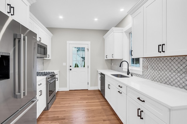 kitchen featuring backsplash, white cabinets, sink, light wood-type flooring, and appliances with stainless steel finishes