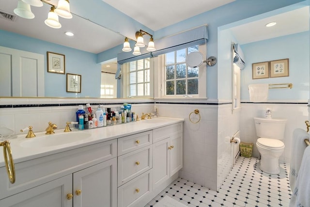 bathroom featuring visible vents, tile walls, and a sink